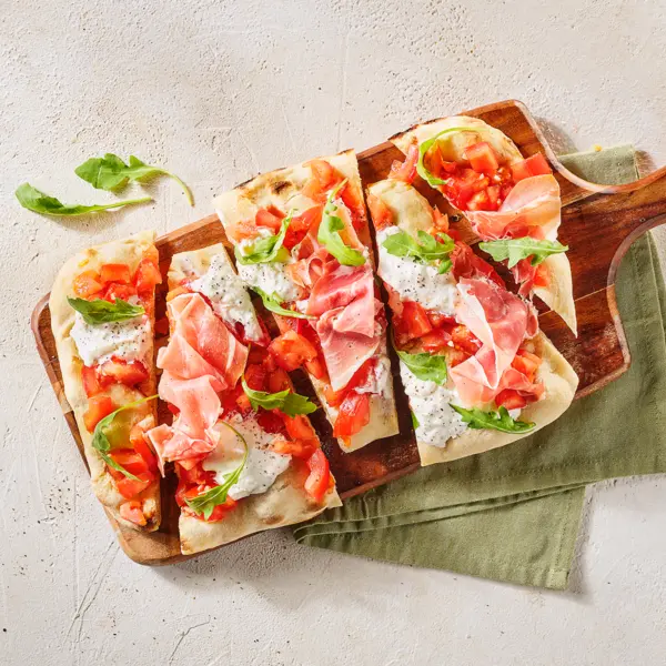 Pinsas au prosciutto et à la burrata à la salsa de tomates et roquette
